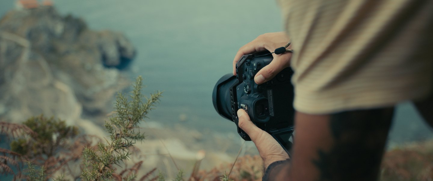 Person photographs coastal landscape with professional camera.